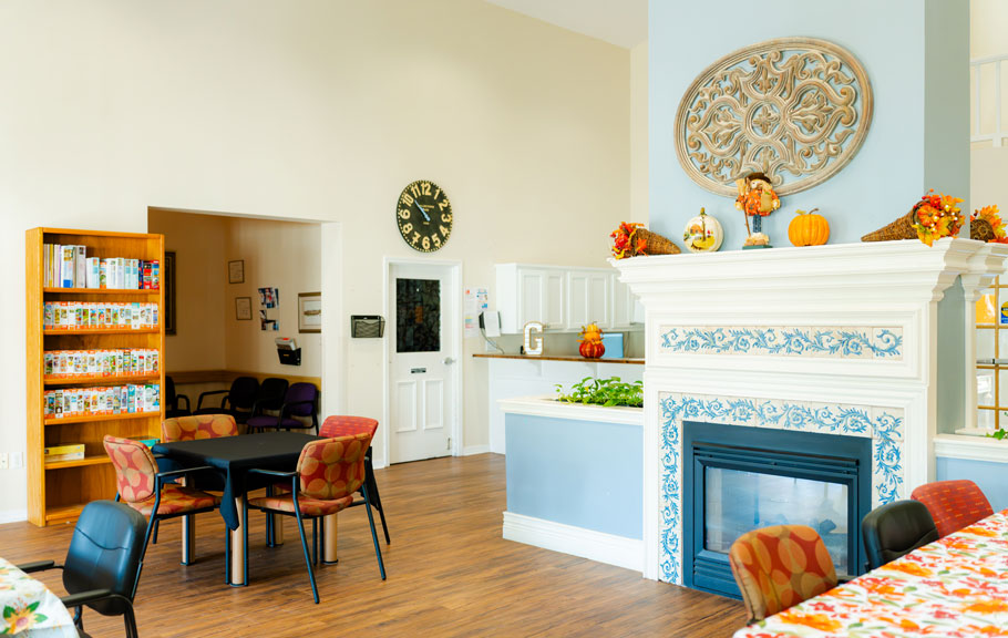 activity room with tables, bookshelf filled with puzzles, and a fireplace